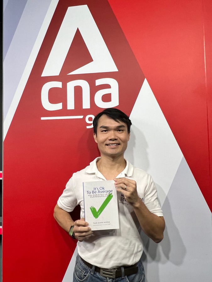 Tan Chin Hock at Channel News Asia holding his book It's Ok To Be Average